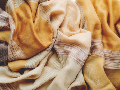 Pastel brown colored scarf. Folded beige warm accessory. Textile background. Top view, flat lay.