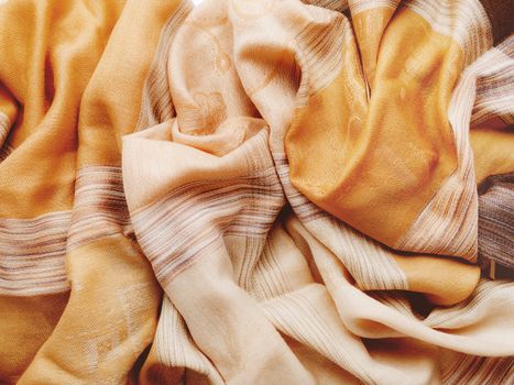 Pastel brown colored scarf. Folded beige warm accessory. Textile background. Top view, flat lay.