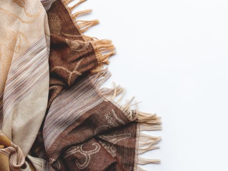 Beige and brown scarf on white background. Folded warm accessory with copy space.