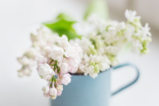 Lilac (Syringa) flowers in old rusty mug. Spring background with white and violet flowers in rustic cup.