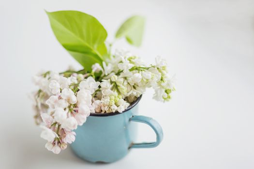 Lilac (Syr�nga) flowers in old rusty mug. Natural spring background with white and violet flowers in rustic cup. Place for text.