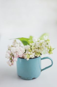Lilac (Syr�nga) flowers in old rusty mug. Natural spring background with white and violet flowers in rustic cup. Place for text.