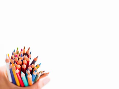 Hand with bunch of colorful pencils on white background. School supplies on white background. Kid's stationery. Back to school copy space backdrop.