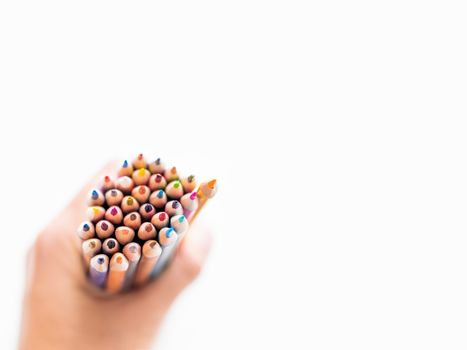 hand with bunch of colorful pencils on white background. School supplies. Kid's stationery with copy space. Back to school backdrop.