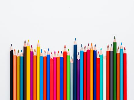 Row of colorful watercolor pencils on white background. School supplies on light paper background. Kid's stationery with copy space. Back to school backdrop.