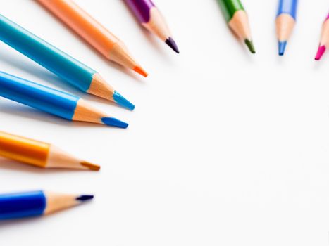 Colorful watercolor pencils on white background. School supplies with round copy space. Kid's stationery. Back to school circle backdrop.
