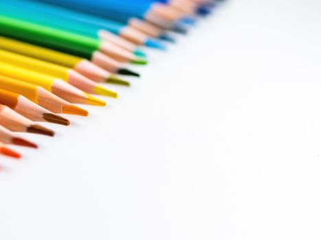 Row of colorful watercolor pencils on white background. School supplies. Kid's stationery with copy space. Back to school backdrop.