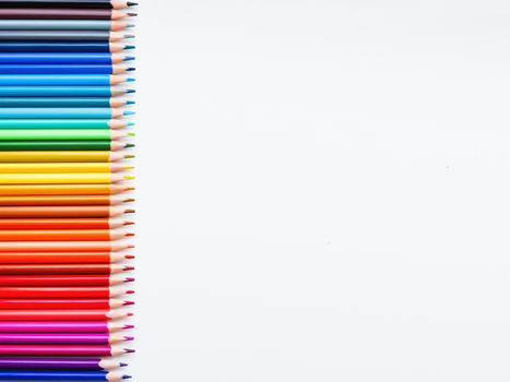 Horizontal row of colorful pencils on white background. School supplies in colores of rainbow. Kid's stationery with copy space. Back to school backdrop.