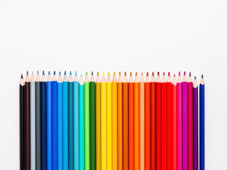 Vertical row of colorful pencils on white background. School supplies in colores of rainbow. Kid's stationery with copy space. Back to school backdrop.