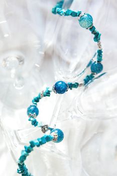 Women jewelry with blue natural stones. Agate beads on clear transparent wineglasses.