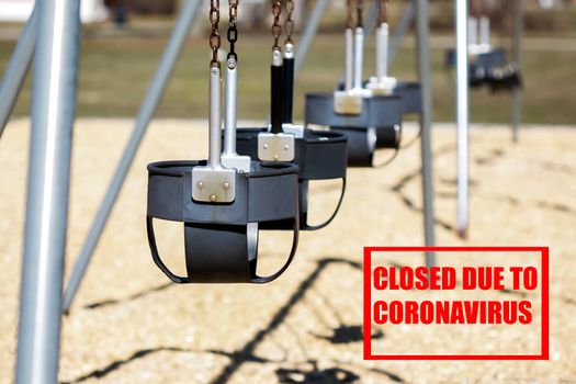 Empty swing seat on outside playground with red text closed due to coronavirus