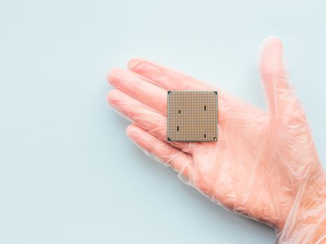 Hand in transparent rubber glove with Central Computer Processor. CPU on light blue background. Technological detail of personal computer.