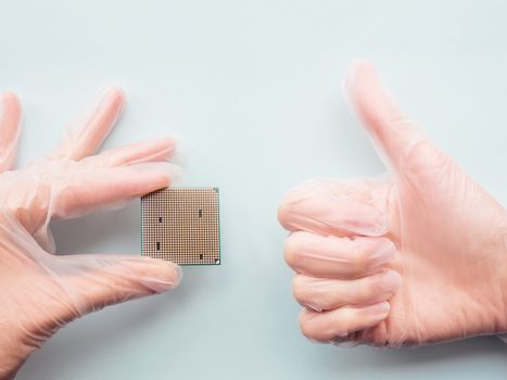 Hands in rubber glove with Central Computer Processor. CPU on light blue background. Technological detail of personal computer.