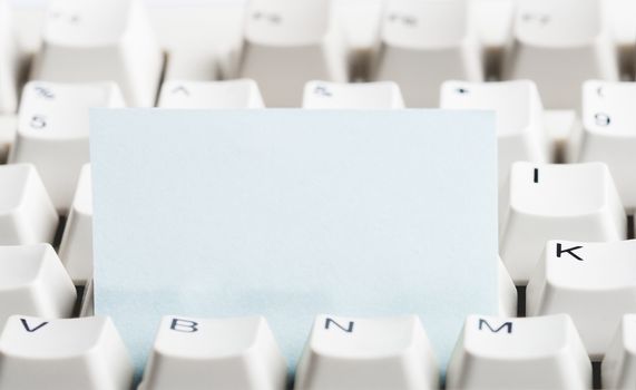 Clear paper stacked in white computer keyboard. May be used as mock up for note or message.