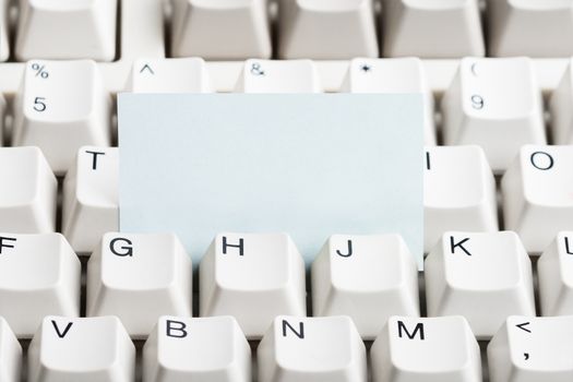 Clear paper stacked in white computer keyboard. May be used as mock up for note or message.