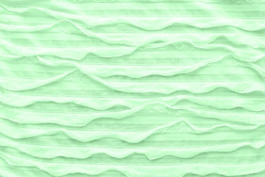 Abstract textile background. Neo mint colored fabric with ruche. Top view, flat lay.