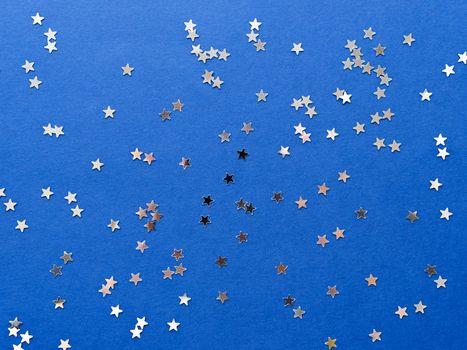 Holiday background with silver star confetti on blue background. Good backdrop for Christmas and New Year cards.