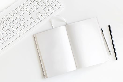 Top view on white table with keyboard, copybook with blank pages and pen with pencil. Flat lay.