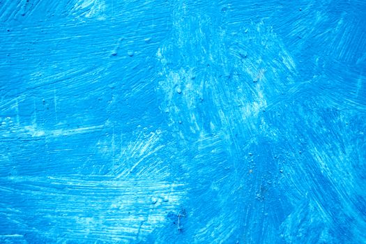 Abstract background with textured strokes of blue paint on the wooden surface.