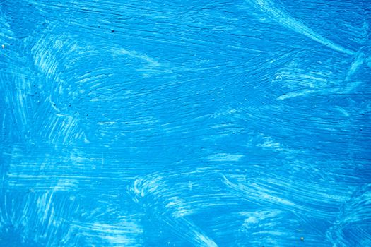 Abstract background with textured strokes of blue paint on the wooden surface.