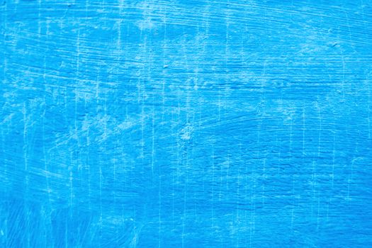 Abstract background with textured strokes of blue paint on the wooden surface.