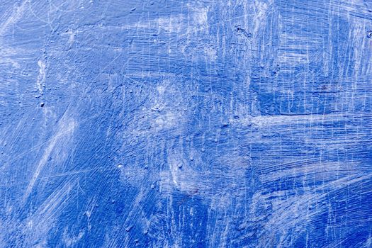 Abstract background with textured strokes of blue paint on the wooden surface.