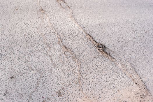 Crack in asphalt. Damaged pavement. Poor condition of the road surface.