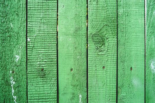 Wooden background of old fence with rusty nails. Shabby texture of green colored wooden boards.