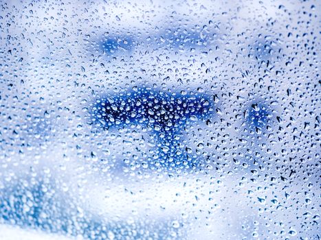 Rain drops on glass. Silhouettes of blue water drops on a transparent surface.