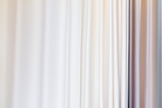 Pastel colored curtains on window. Textile folds of drapery.