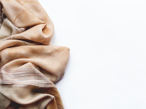 Beige and brown scarf on white background. Folded warm accessory with copy space.