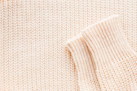Abstract knitted background. Wool sweater with sleeves. Close up picture of knitted pattern.
