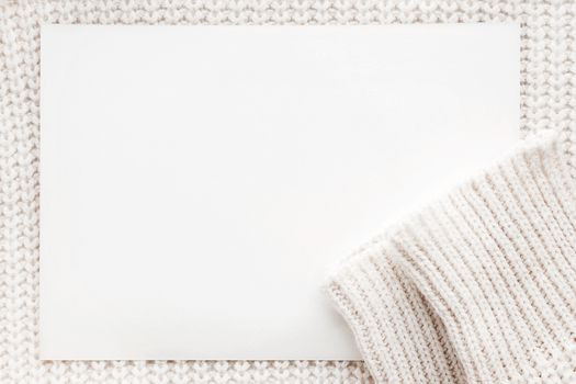 Abstract knitted background with clear paper. White woolen sweater with sleeves. Close up picture of knitted pattern.