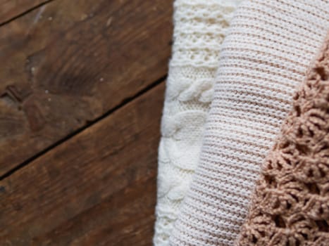 Grey and white knitted sweaters on shabby wooden background. Top view, flat lay.