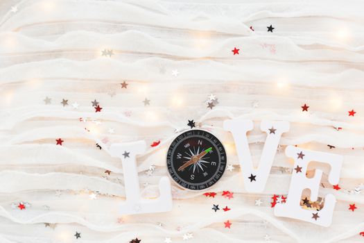 Love background. Travel symbol - compass and confetti on white fabric. Flat lay, top view.