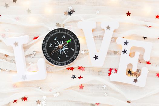 Love background. Travel symbol - compass and confetti on white fabric. Flat lay, top view.