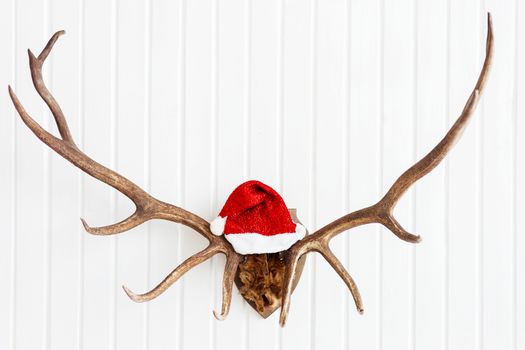 Deer antler with bright red Santa's hat. Christmas detail of home interior.