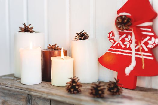 Christmas and New Year background with candles, pine cones and red Eve Tree with nordic pattern. Lovely holiday details of home interior.