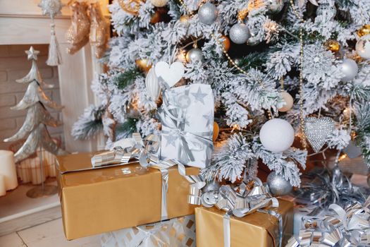 Christmas and New Year background with presents under the Eve Tree. Holiday winter background. Many gifts wrapped in golden and silver paper with bows.