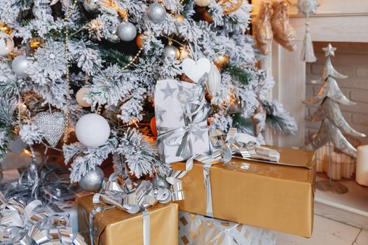 Christmas and New Year background with presents under the Eve Tree. Holiday winter background. Many gifts wrapped in golden and silver paper with bows.