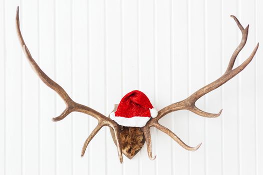 Deer antler with bright red Santa's hat. Christmas detail of home interior.