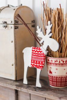 White wooden deer in knitted sweater with nordic pattern. Christmas and New Year decorative detail of interior.