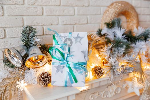 Christmas and New Year decorations on mantelpiece. Holiday winter background with wrapped present. Gift with paper bow.