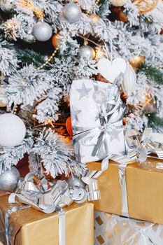Christmas and New Year background with presents under the Eve Tree. Holiday winter background. Many gifts wrapped in golden and silver paper with bows.