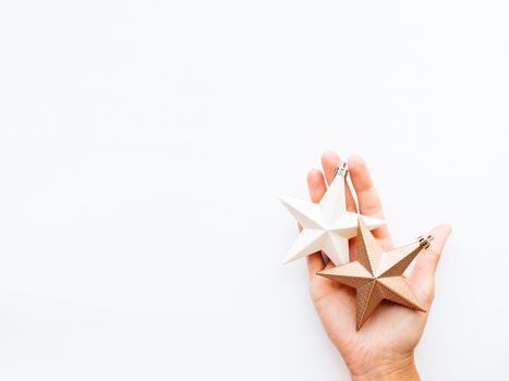 Woman is holding New Year decoration - two stars on white background. Top view on decoration for Christmas tree.