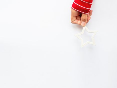 Woman in red sweater is holding New Year decoration - white star on white background. Top view on decoration for Christmas tree.