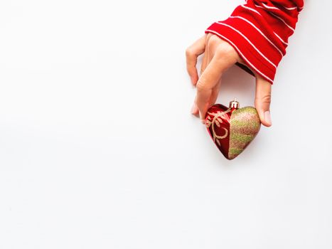 Woman is holding New Year decoration - red heart on white background. Top view on decoration for Christmas tree.