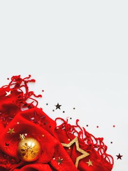 Christmas and New Year background. Bright red scarf with golden stars and confetti on white background. Folded warm accessory with copy space.