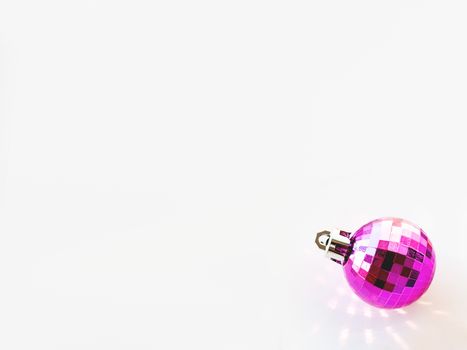 New Year background with magenta ball. Pink reflections, sunbeams on white copy space with decorative ball for Christmas tree.
