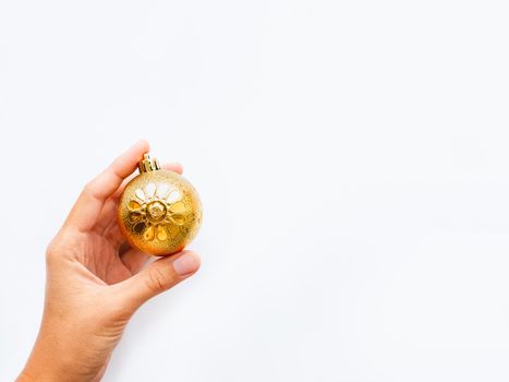 Woman is holding New Year decoration - golden ball on white background. Top view on decoration for Christmas tree.
